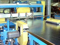 This picture shows the two side trims saws in the foreground and the flying cutoff saw in the middle of a cut in the background. Click to enlarge.