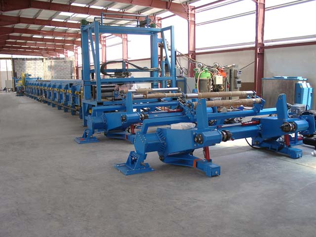 Another type of unwind stand feeds substrate to this process line. Beyond are the traverse for the mixing and dispensing head and the Foamboarder.