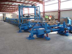 Another type of unwind stand feeds substrate to this process line. Beyond are the traverse for the mixing and dispensing head and then the Foamboarder.