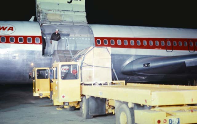 Here aircraft cargo is transferring from one high-lift cargo lift truck to another and then is loaded onto the aircraft.